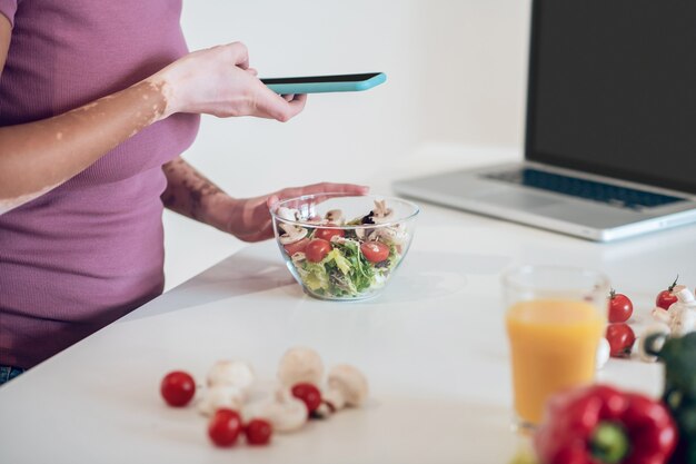 Photo à poster. Une femme à la peau foncée faisant une photo d'une salade