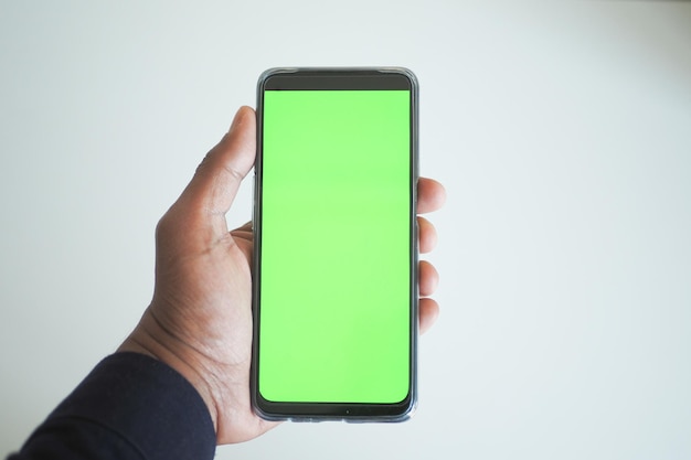 photo pov d'une main de jeune homme utilisant un téléphone intelligent avec écran vert