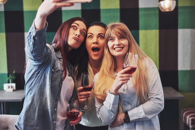 Photo présentant un groupe d'amis heureux avec du vin rouge prenant selfie