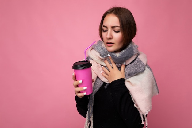 Photo prise de belle jeune femme brune triste portant un pull noir et une écharpe chaude isolée sur