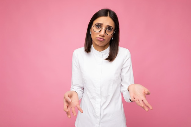 Photo prise de vue de la belle jeune femme brune triste portant chemise blanche et lunettes optiques élégantes