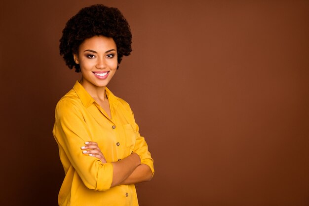 Photo photo de profil de belle entreprise drôle peau foncée curly lady rayonnant souriant bras croisés bonne humeur travailleur fiable porter chemise jaune couleur marron