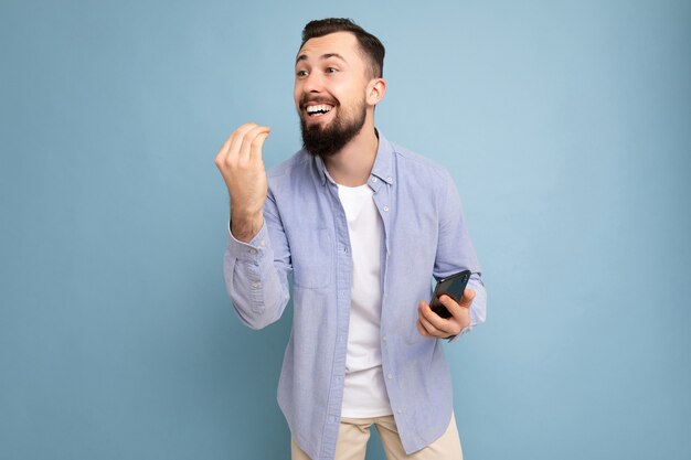 Photo de profil de côté d'émotionnel positif beau jeune homme barbu brunet portant du bleu décontracté