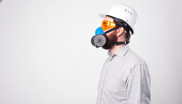 Photo de profil d'un homme en chemise portant un casque blanc et respirant à travers le respirateur