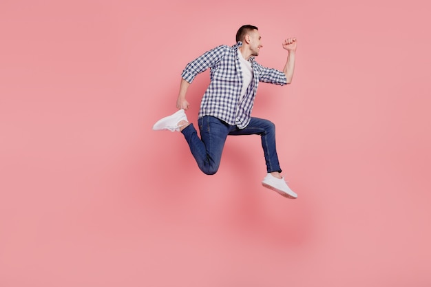 Photo de profil pleine longueur de jeune homme heureux sourire positif sautant courir pressé isolé sur fond de couleur rose