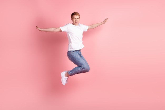 Photo de profil pleine taille d'un jeune homme gai s'amuser avec les mains saut à la mouche isolé sur fond de couleur rose