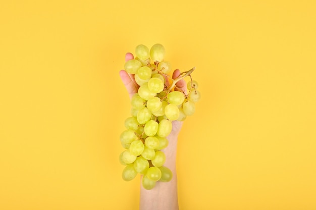 Photo de raisin vert sur fond jaune. Raisins volumétriques. Une grappe de raisin vert.