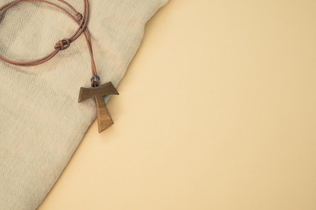 Une photo rapprochée d'un collier de croix de tau en bois sur un fond en bois