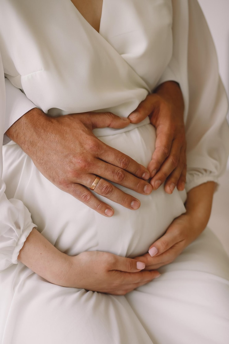 Photo une photo rapprochée d'un homme qui fait la forme d'un cœur avec les mains sur le ventre enceinte de sa femme concept d'amour