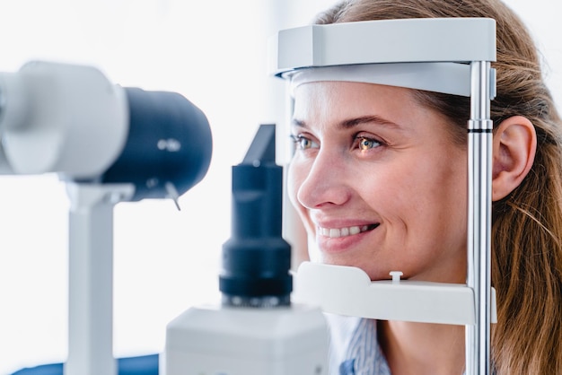 Photo une photo rapprochée d'une jeune femme souriante lors d'un examen de la vue ophtalmologique