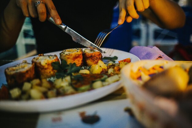 Une photo rapprochée d'une personne coupant des rouleaux de légumes d'un plat gourmet