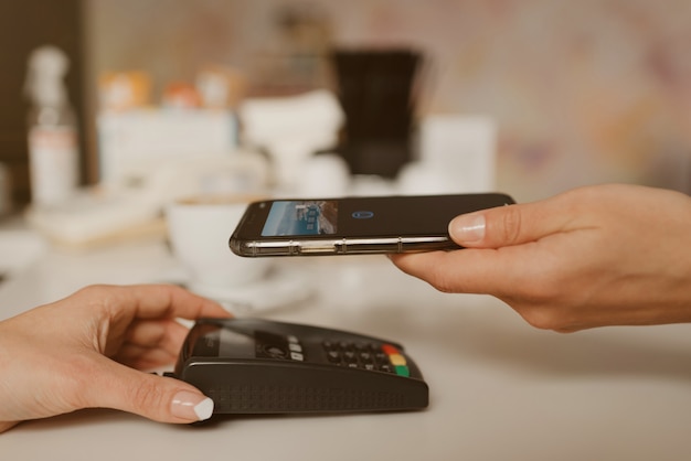 Une photo rapprochée d'un smartphone se préparant à payer par la technologie sans contact dans un café