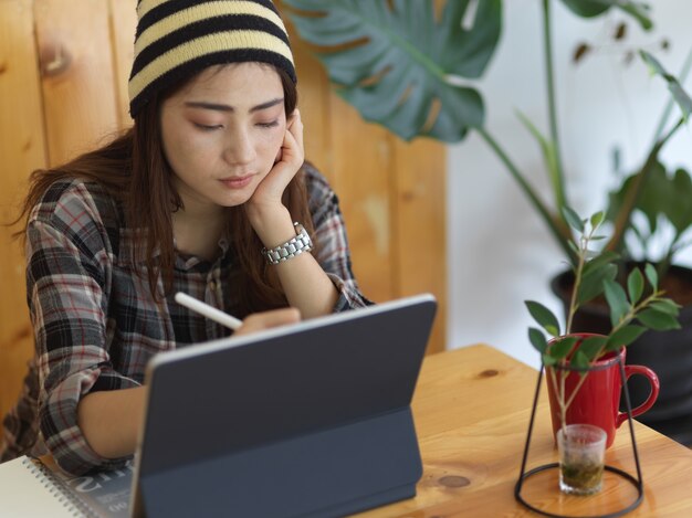 Photo recadrée d'une adolescente à l'aide de tablette avec stylet dans un café