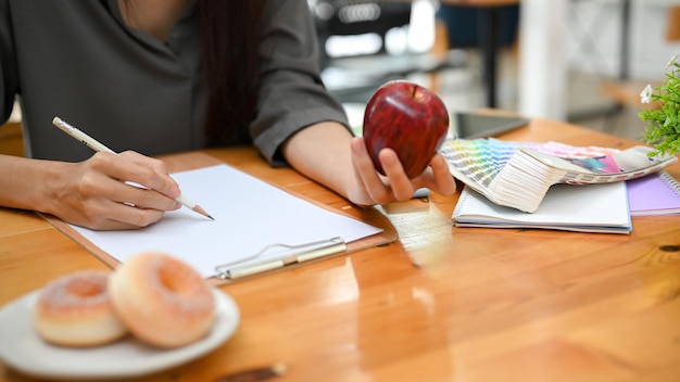 Photo recadrée Une artiste ou graphiste dessinant une forme de pomme sur son papier vierge