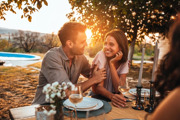 Photo recadrée d'un beau couple en train de dîner avec des amis dans l'arrière-cour