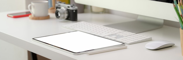 Photo recadrée d'un bureau confortable avec une tablette à écran vierge et des appareils informatiques