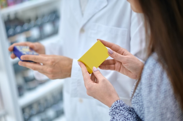 Photo recadrée d'une cliente aux cheveux noirs et d'un pharmacien vêtu d'une robe blanche tenant des barres de savon dans leurs mains