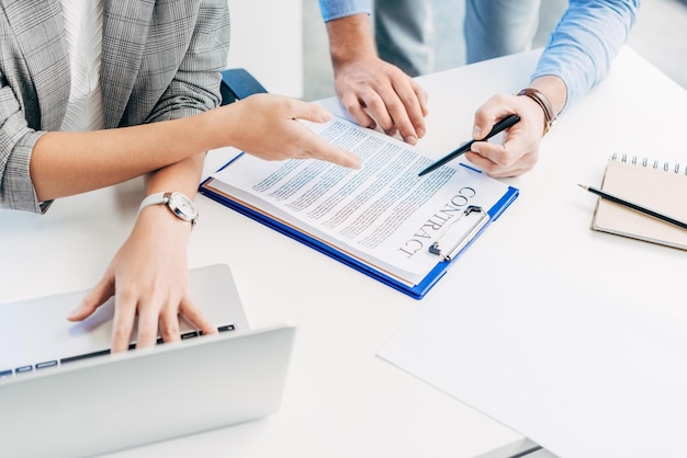 Photo recadrée de collègues de travail travaillant avec un contrat et un ordinateur portable