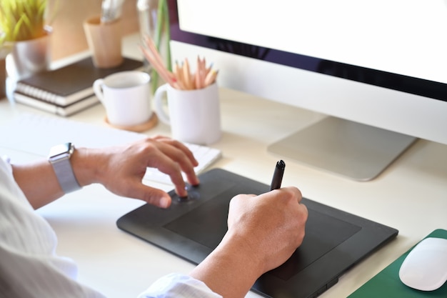 Photo recadrée d&#39;un designer travaillant avec une tablette à dessin numérique pour un design créatif au bureau