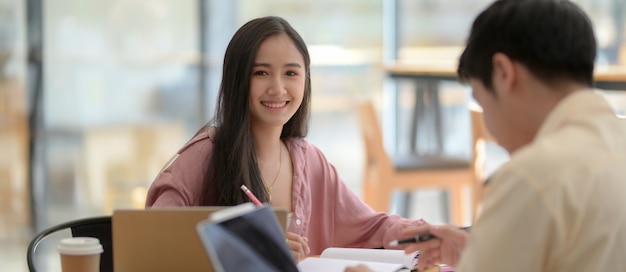 Photo recadrée d'une étudiante heureuse, assise en face de son amie