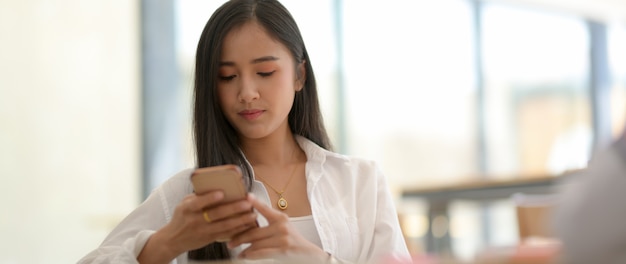 Photo recadrée d'étudiants universitaires prenant un peu de temps avec un smartphone pour se détendre