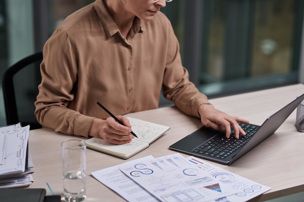 Photo recadrée d'une femme courtier ou analyste expérimentée en informatique au bureau