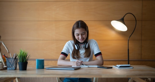 Photo recadrée d'une femme écrivant faisant une liste prenant des notes dans un bloc-notes travaillant ou apprenant sur un ordinateur portable à l'intérieur d'un cours éducatif ou d'un séminaire de formation concept en ligne d'éducation