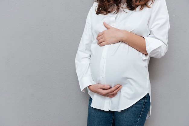 Photo recadrée de femme enceinte en studio isolé sur fond gris