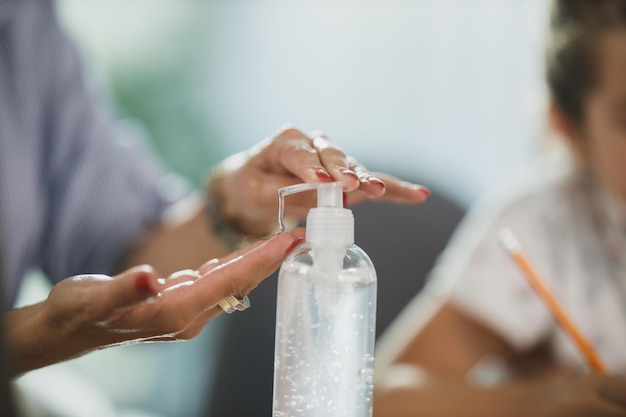 Photo recadrée d'une femme méconnaissable utilisant un gel antiseptique pour se désinfecter les mains à son bureau à domicile pendant la pandémie du virus corona.