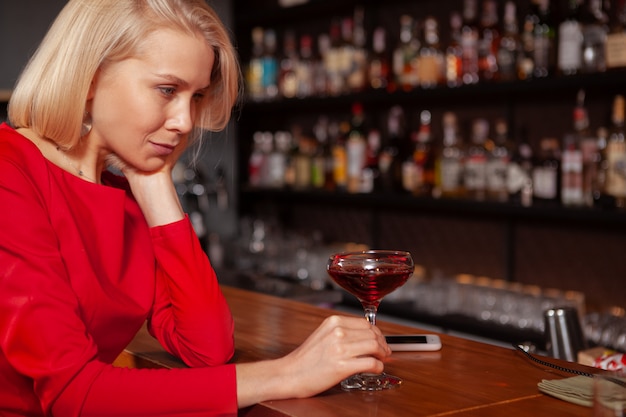 Photo recadrée d'une femme triste buvant au bar. Femme déprimée ayant un cocktail seul au restaurant