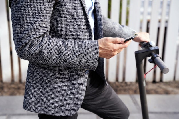 Photo recadrée d'un homme d'affaires élégant d'âge moyen tenant son smartphone debout avec son