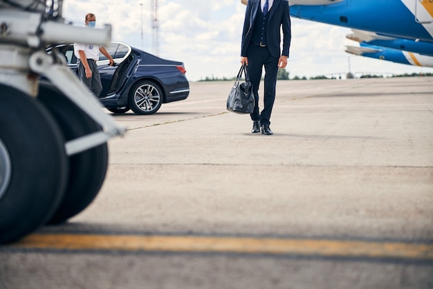 Photo recadrée d'un homme d'affaires portant un sac de sport en passant devant les avions
