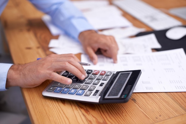 Photo recadrée d'un homme d'affaires utilisant une calculatrice dans son bureau