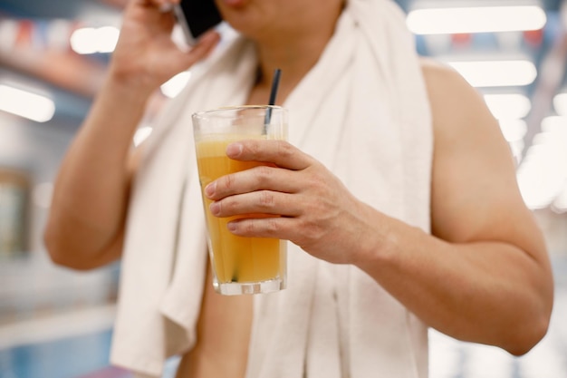 Photo recadrée d'un homme debout dans la piscine tenant un verre de jus