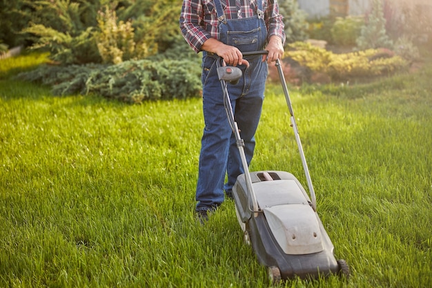 Photo recadrée d'un jardinier travailleur déplaçant une pelouse avec un coupe-herbe