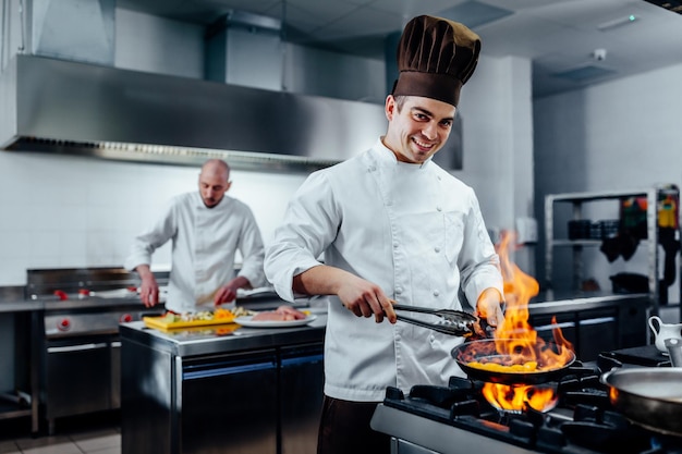 Photo recadrée d'un jeune chef masculin préparant le repas dans une cuisine professionnelle