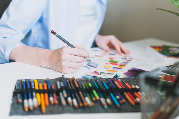 Photo recadrée d'une jeune femme aux cheveux rouges artiste illustrateur dessine au bureau au bureau à domicile