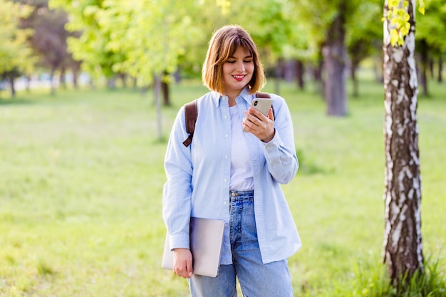 Photo recadrée d'une jeune femme mains bras porter une chemise bleue tapant un appareil moderne se reposant