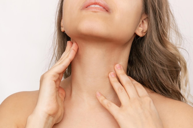 Une photo recadrée d'une jeune femme massant le cou avec ses mains à l'aide d'une crème pour hydrater la peau