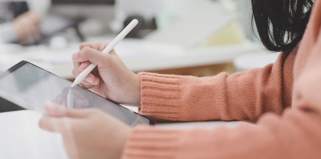 Photo recadrée de jeune femme travaillant sur son projet actuel avec tablette