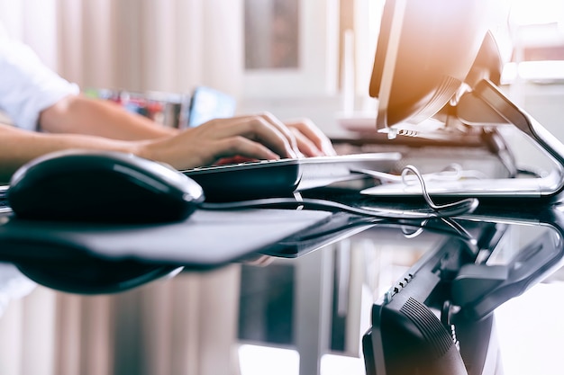 Photo recadrée de la main de l&#39;homme tapant sur le clavier de l&#39;ordinateur noir assis sur le lieu de travail