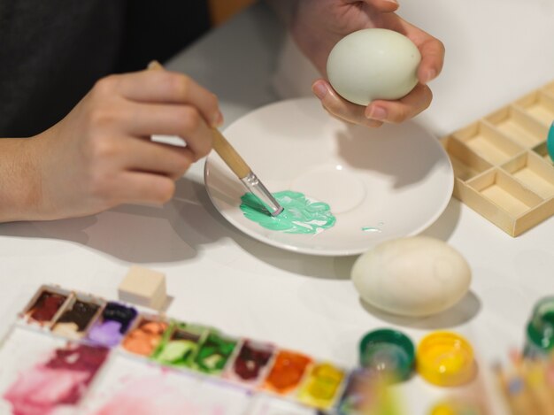 Photo recadrée de mains peinture oeuf avec la couleur de l'affiche se préparant pour le festival de Pâques