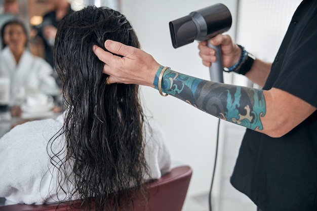 Photo recadrée des mains tatouées du coiffeur