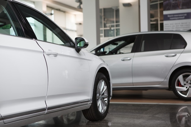 Photo recadrée de nouvelles voitures méconnaissables garées dans un salon de concession automobile