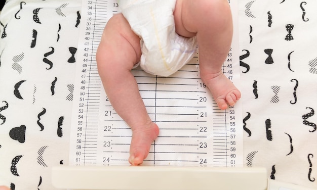 Photo recadrée d'un pédiatre examinant un bébé nouveau-né Médecin utilisant un ruban de mesure vérifiant la taille de bébé Gros plan