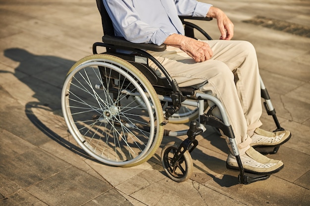 Photo recadrée d'un retraité utilisant un fauteuil roulant tout en passant du temps en ville