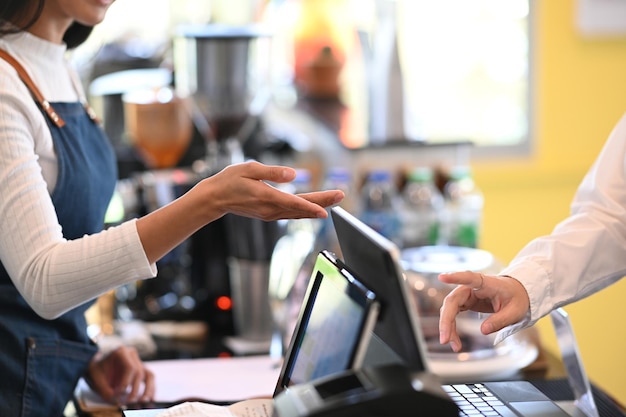 Photo recadrée d'une serveuse hospitalière lui recommandant de commander quelque chose de spécial dans un café.