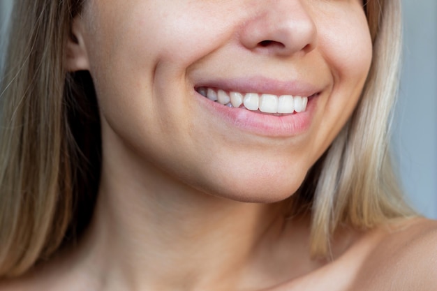 Photo recadrée d'un visage d'une jeune femme blonde souriante avec des fossettes sur les joues
