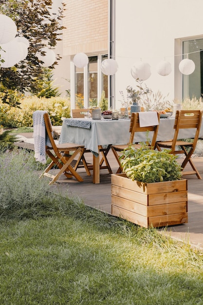 Photo réelle d'un jardin avec une table, des chaises, des lampes et une boîte en bois avec des plantes