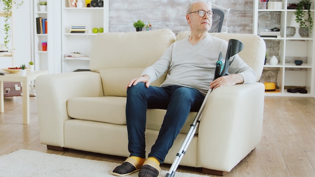 Photo révélatrice d'un infirmier surveillant un vieil homme à la retraite avec alzheimer assis sur un canapé dans la maison de soins infirmiers